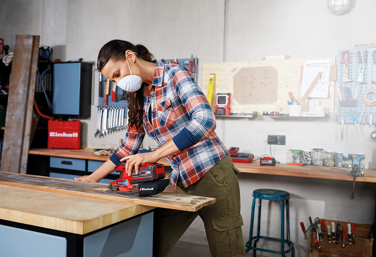 Απεικονίζεται γυναίκα να χρησιμοποιεί το τριβείο σε ξύλινη επιφάνεια, μέσα σε εργαστήριο.